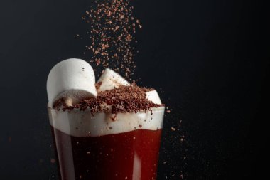 Çikolata kırıntıları serpiştirilmiş kremalı sıcak çikolata. Siyah arka plan. Boşluğu kopyala.