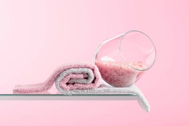 Pembe arka planda pembe tuz ve havlu içeren spa kompozisyonu. Boşluğu kopyala.