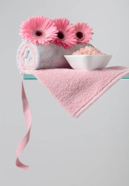 Pembe tuz, çiçek ve havluyla spa kompozisyonu.