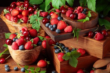Yapraklı taze böğürtlen. Eski bir masada çilek, ahududu, yabanmersini ve tatlı kirazlar.. 