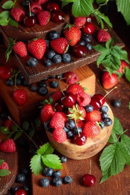 Yapraklı taze böğürtlen. Eski bir masada çilek, ahududu, yabanmersini ve tatlı kirazlar.. 