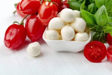 Beyaz ahşap bir masada fesleğen ve domatesli Mozzarella peyniri..