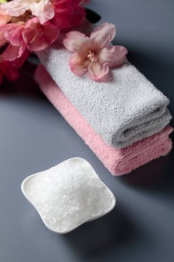 Deniz tuzu, çiçek ve havluyla spa kompozisyonu.