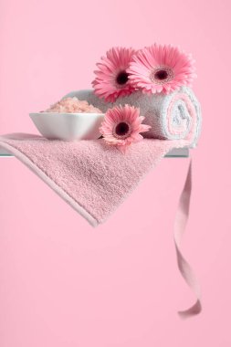 Pembe tuz, çiçek ve havluyla spa kompozisyonu.