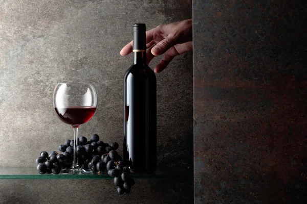 Bir şişe kırmızı şaraba uzanır. Pahalı şarapların konsepti. Metnin için boş yer.