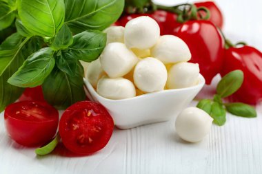 Beyaz ahşap bir masada fesleğen ve domatesli Mozzarella peyniri..