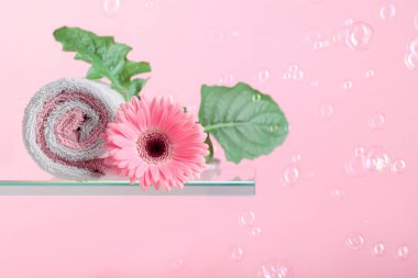 Pembe gerberli spa kompozisyonu ve köpüklü pembe arka planda havlular. Boşluğu kopyala.