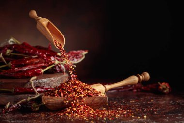 Biberler ahşap bir tabağa dökülür. Kahverengi arka planda kırmızı biber ve kırmızı biber..