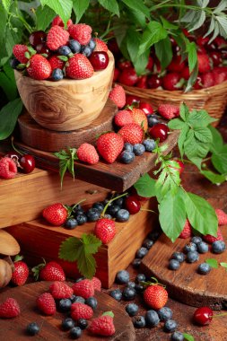Yapraklı taze böğürtlen. Eski bir masada çilek, ahududu, yabanmersini ve tatlı kirazlar.. 