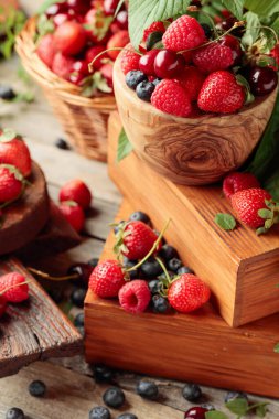 Yapraklı taze böğürtlen. Çilek, ahududu, böğürtlen ve kirazlar eski ahşap bir masada.. 