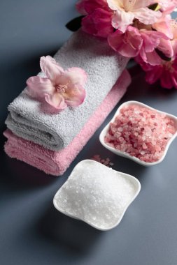 Pembe ve beyaz deniz tuzu, çiçek ve havluyla spa kompozisyonu.