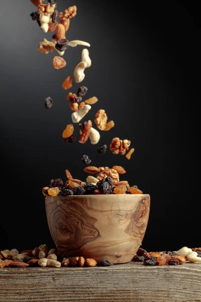 Flying dried fruits and nuts. The mix of nuts and raisins in a wooden bowl.