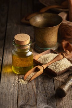 Susam tohumu ve yağ. Eski ahşap bir masada mutfak aletleriyle susam yağı..