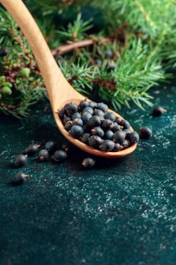 Koyu mavi bir masada ardıç tohumlarıyla ahşap kaşık.