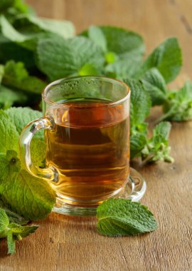 Mint tea in glass on a wooden table.