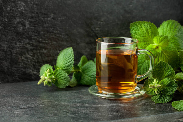 Мятный чай в стакане на черном столе. Копирование пространства.