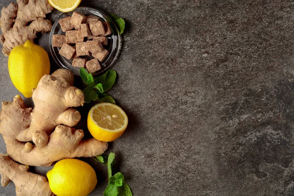 Ingredients for ginger tea. Ginger, lemon, mint and brown sugar on vintage background. Top view.