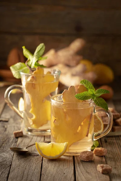 Ginger tea with ingredients. Ginger, lemon, mint and brown sugar on an old wooden table.