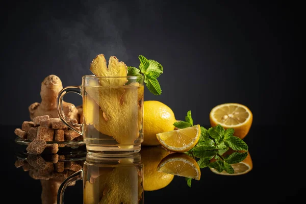 Ginger tea with ingredients. Ginger, lemon, mint, and brown sugar on a black background. Copy space.