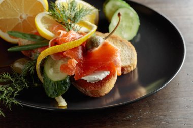 Somonlu sandviç, krem peynir, dereotu, salatalık, kapari, yeşil soğan ve limon..