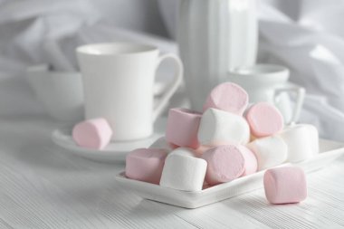 Mutfak aletleriyle ahşap bir masada pembe ve beyaz şekerlemeler..