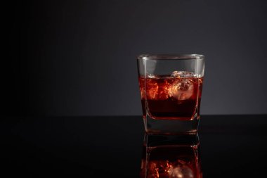 Siyah yansıtıcı arka planda buzlu viski. Boşluğu kopyala.