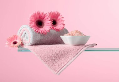 Pembe tuz, çiçek ve havluyla spa kompozisyonu.