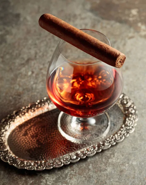 Snifter of brandy and cigar on an old stone table. Copy space.