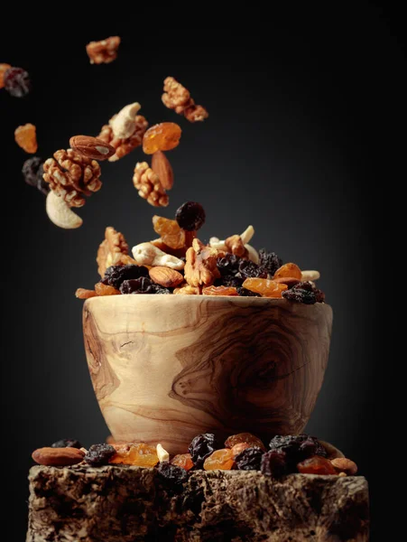 Flying dried fruits and nuts. The mix of nuts and raisins in a wooden bowl.