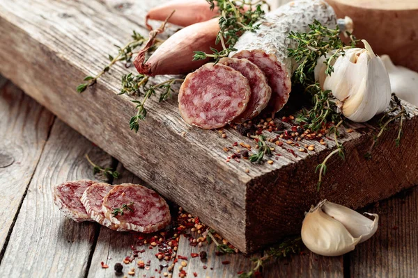 Traditional dry-cured sausage with thyme, garlic, onion, and spices. Dry-cured sausage on a old wooden table.
