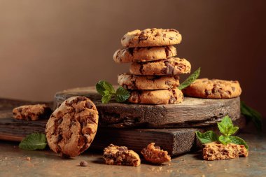 Freshly baked chocolate cookies with mint on a rustic brown background. Copy space.
