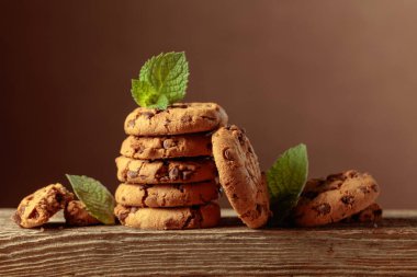 Freshly baked chocolate cookies with mint on an old wooden table. Copy space.