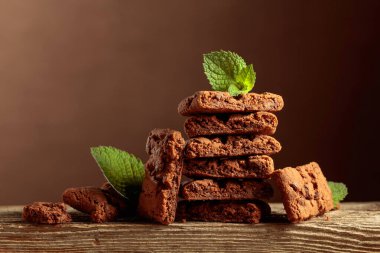 Pieces of fresh baked brownie with mint on a wooden table. Copy space.