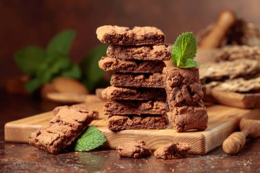 Pieces of fresh brownie with mint on an old table with kitchen utensils.