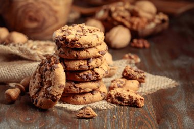 Freshly baked chocolate cookies on a wooden table with kitchen utensils.
