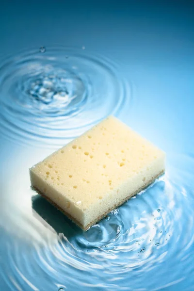 New and clean sponge falls into the water forming waves. Clean concept. Copy space.