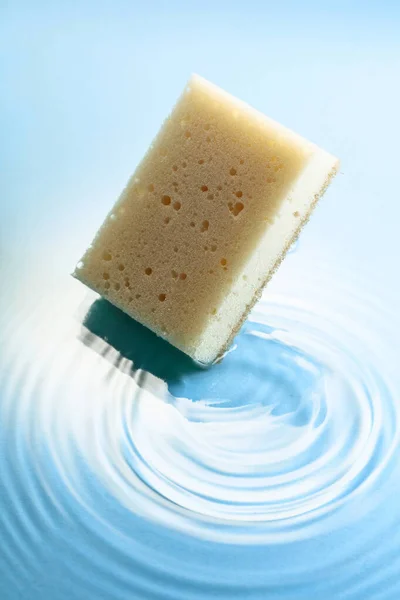 New and clean sponge falls into the water forming waves. Clean concept.
