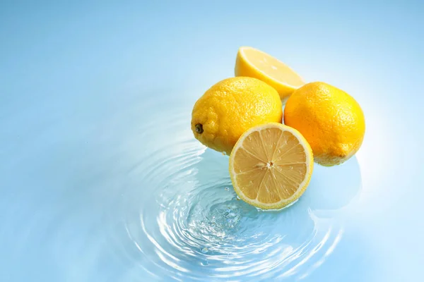 Ripe juicy lemons on a blue background with water splashes. Copy space.