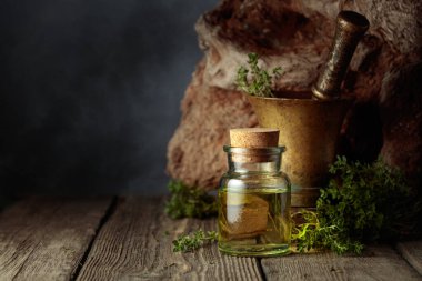 Bottle of thyme essential oil with fresh thyme twigs on an old wooden table. Copy space.