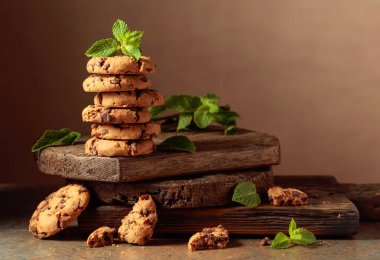 Freshly baked chocolate cookies with mint on a rustic brown background. Copy space.