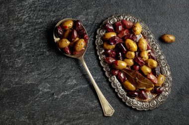 Spicy olives on a black stone table. Top view.