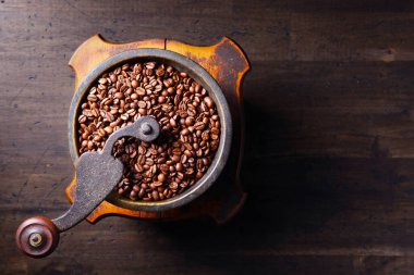 Old coffee grinder and roasted coffee beans, top view, free space for your text.