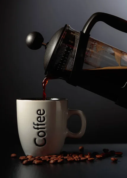 Pouring French press coffee into a cup on a black table. Copy space.