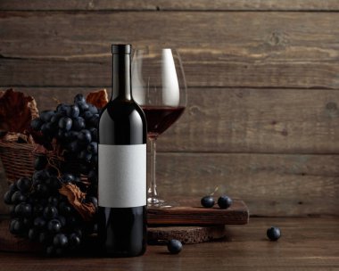 Red wine and blue grapes. Wine and grapes in a vintage setting. On a bottle empty label. Copy space.