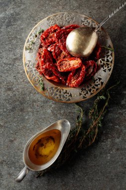 Zeytinyağında güneşte kurutulmuş domatesler ve eski bir taş masanın üzerinde kekik. Üst görünüm.