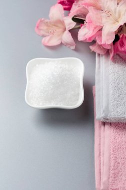 Deniz tuzu, çiçek ve havluyla spa kompozisyonu.