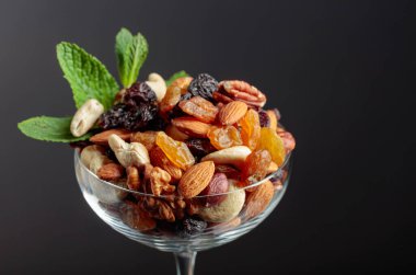 Cam bir kasede fındık ve kuru üzüm karışımı siyah arka planda naneyle süslenir..