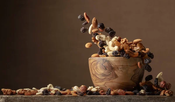 Flying dried fruits and nuts. The mix of nuts and raisins in a wooden bowl. Copy space.