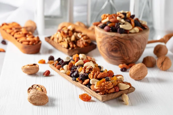 Mix of nuts and raisins on a white wooden table. Presented raisins, walnuts, hazelnuts, cashews, pecans, and almonds.