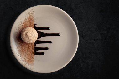 Çikolata sosu ve kakao tozuyla süslenmiş bej bir tabakta makarna. Kopyalama alanı olan siyah taş arkaplan.